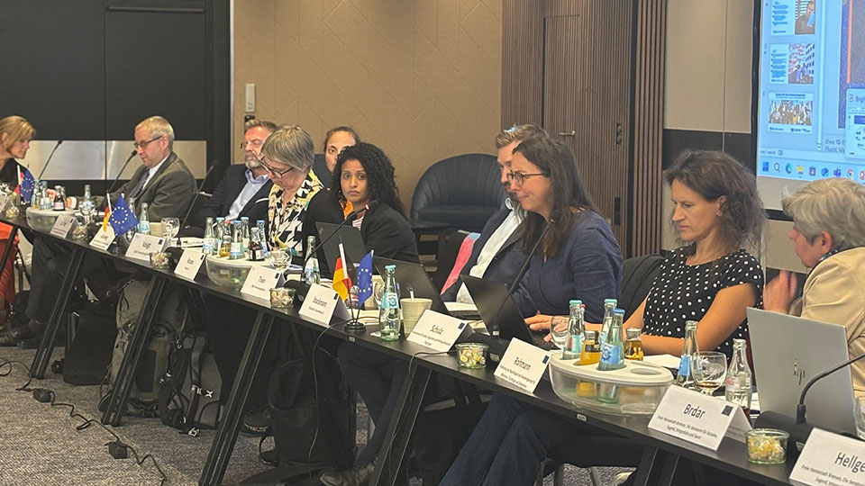 Mehrere Frauen und Männer sitzen an einem Tisch. Vor jeder Person liegt ein Namensschild, daneben stehen Getränke. (Quelle: Bundesamt für Migration und Flüchtlinge) Mehrere Frauen und Männer sitzen an einem Tisch. Vor jeder Person liegt ein Namensschild, daneben stehen Getränke.