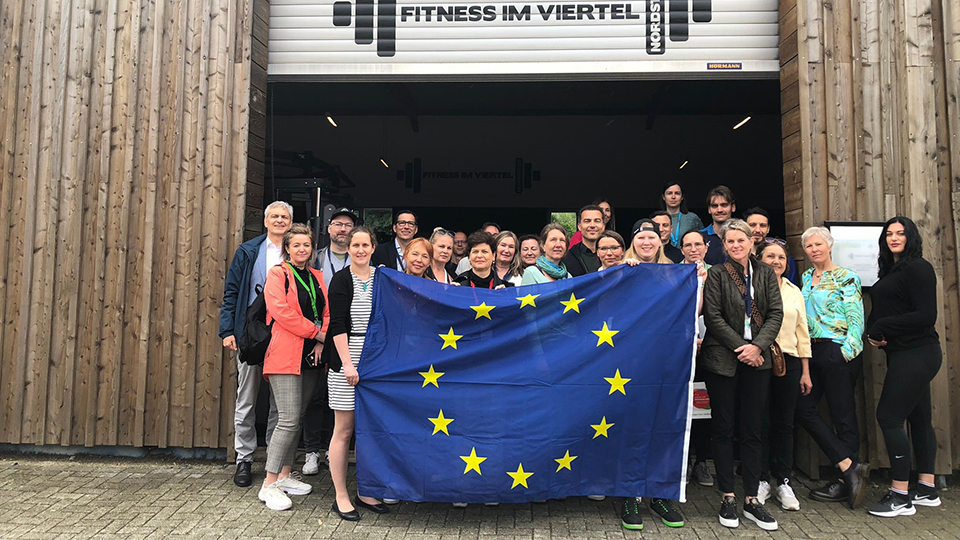 Eine Gruppe von Menschen halten die EU-Flagge vor einem der Projektstandorte hoch. (Quelle: © Europäische Kommission) Eine Gruppe von Menschen halten die EU-Flagge vor einem der Projektstandorte hoch.