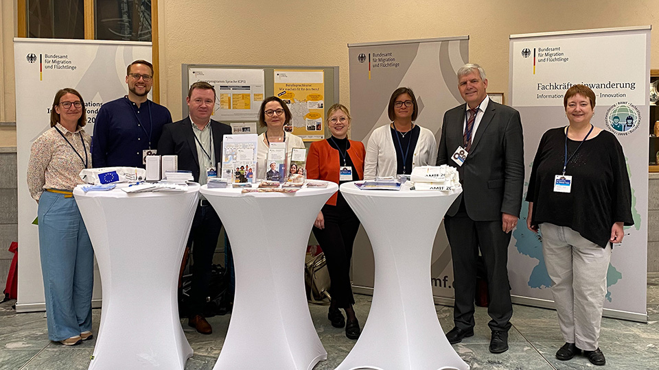 Fünf Frauen und drei Männer stehen an einem Informationsstand. (Quelle: © BAMF) Fünf Frauen und drei Männer stehen an einem Informationsstand.