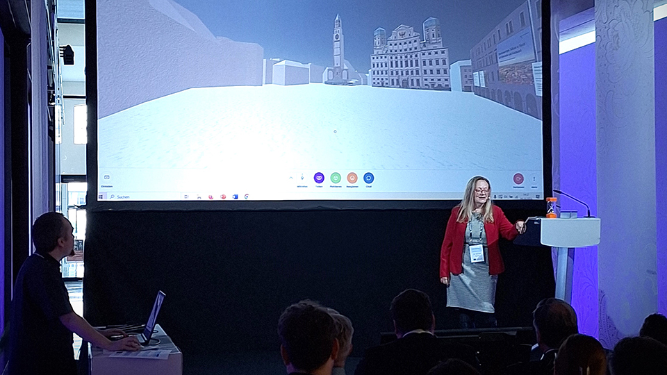 Frau Dr. Margret Spohn spricht vor einer Leinwand zum Publikum. (Quelle: Stadt Augsburg) Frau Dr. Margret Spohn spricht vor einer Leinwand zum Publikum.