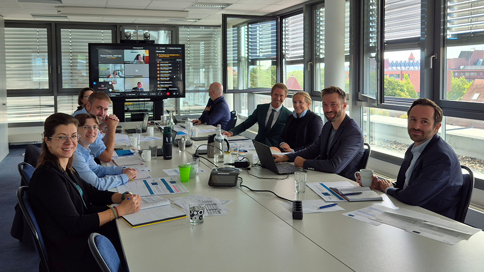 Mehrere Frauen und Männer sitzen um einen Tisch herum. (Quelle: BAMF) Mehrere Frauen und Männer sitzen um einen Tisch herum.