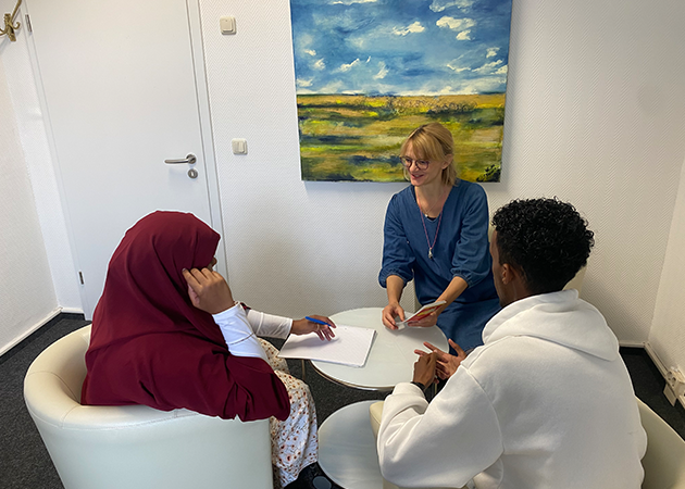 Zwei Frauen und ein Mann sitzen an einem runden Tisch. Eine Frau hält einen Flyer in der Hand, die andere einen Kugelschreiber, auf dem Tisch liegt ein leeres Blatt Papier. (Quelle: Kreisdiakonisches Werk Greifswald e.V.) Zwei Frauen und ein Mann sitzen an einem runden Tisch. Eine Frau hält einen Flyer in der Hand, die andere einen Kugelschreiber, auf dem Tisch liegt ein leeres Blatt Papier.