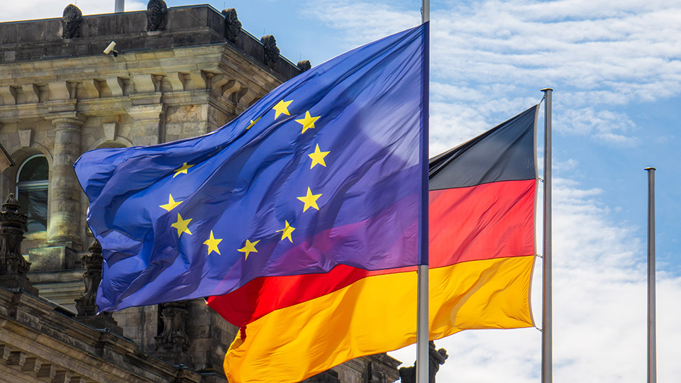 Flaggen von Deutschland und der Europäischen Union wehen im Wind vor dem Reichstag in Berlin.