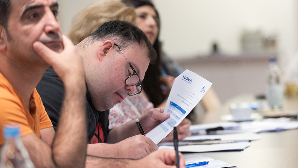 Vier Teilnehmende sitzen nebeneinander an einem Tisch, vor ihnen Unterlagen, einer von ihnen hält ein Blatt in der Hand hält und macht sich Notizen. (Quelle: Handicap International e.V.) Vier Teilnehmende sitzen nebeneinander an einem Tisch, vor ihnen Unterlagen, einer von ihnen hält ein Blatt in der Hand hält und macht sich Notizen.