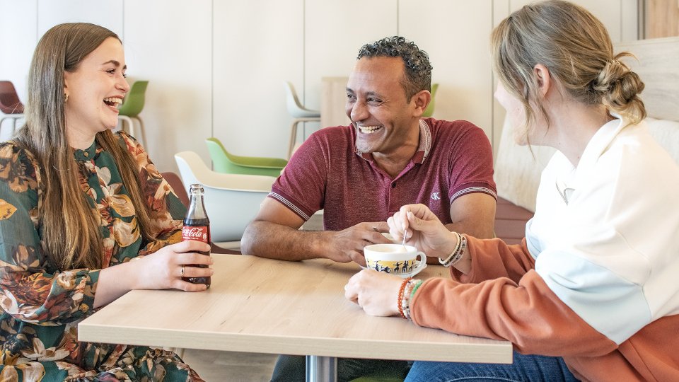Zwei Frauen und ein Mann sitzen lachend an einem Tisch. (Quelle: ed-media e. V.) Zwei Frauen und ein Mann sitzen lachend an einem Tisch.