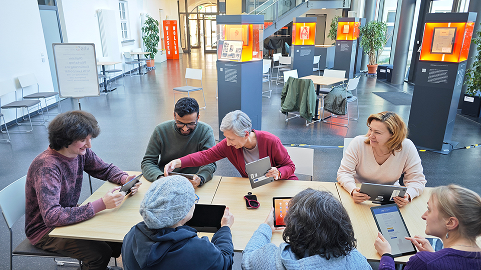 Sieben Personen sitzen an einem Tisch mit Tablets in der Hand. (Quelle: Volkshochschule Hofer Land e.V.) Sieben Personen sitzen an einem Tisch mit Tablets in der Hand.