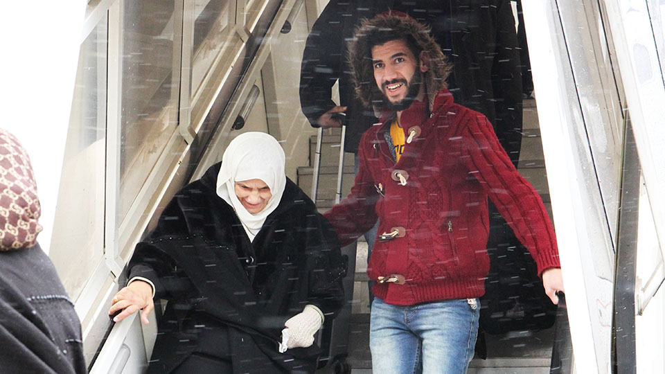 Ein Mann hilft einer älteren Frau die Gangway eines Flugzeuges herunter. (Quelle: Bundesamt für Migration und Flüchtlinge) Ein Mann hilft einer älteren Frau die Gangway eines Flugzeuges herunter.